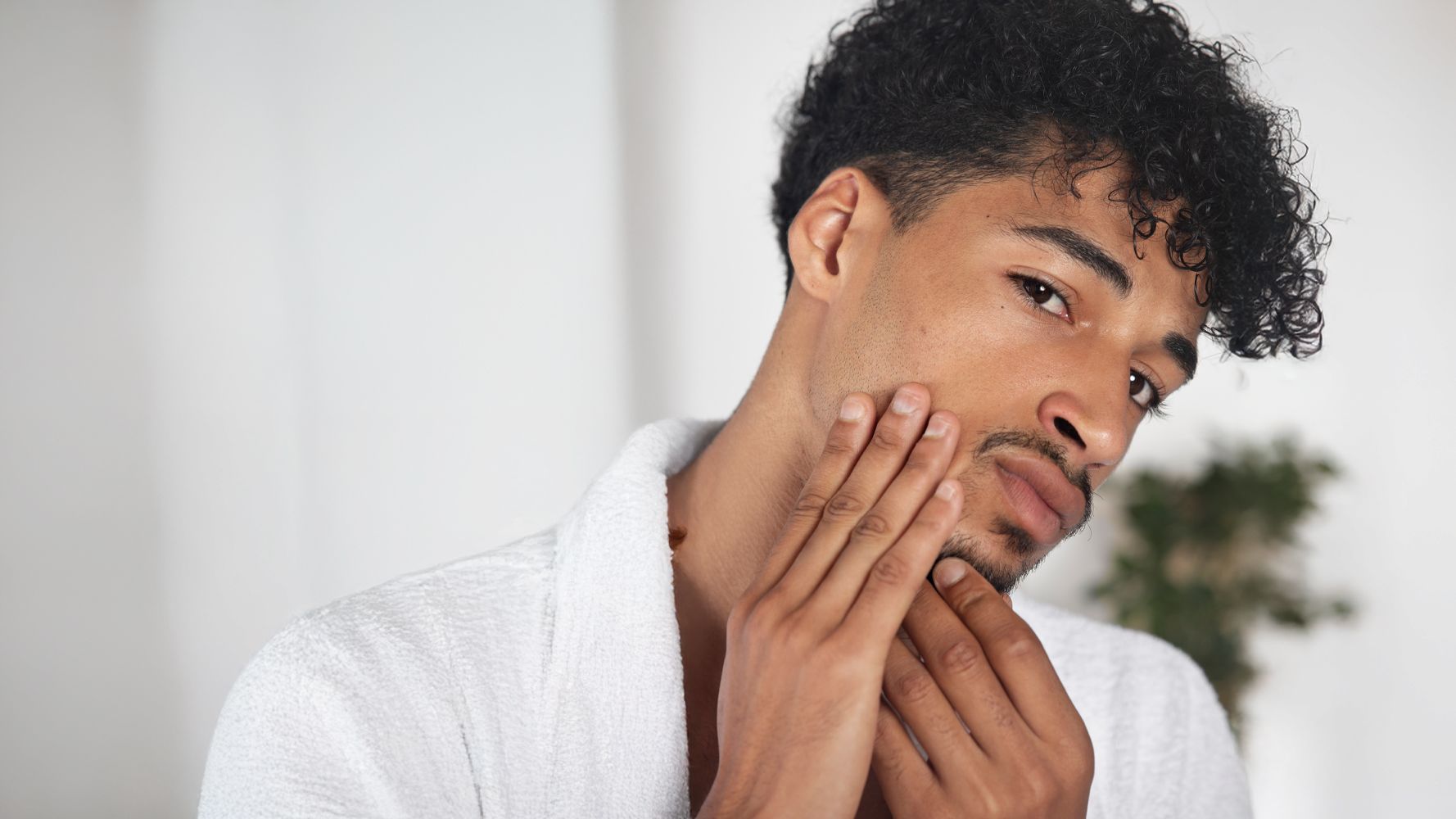 Uomo che applica olio di Argan sulla barba durante la routine quotidiana di grooming